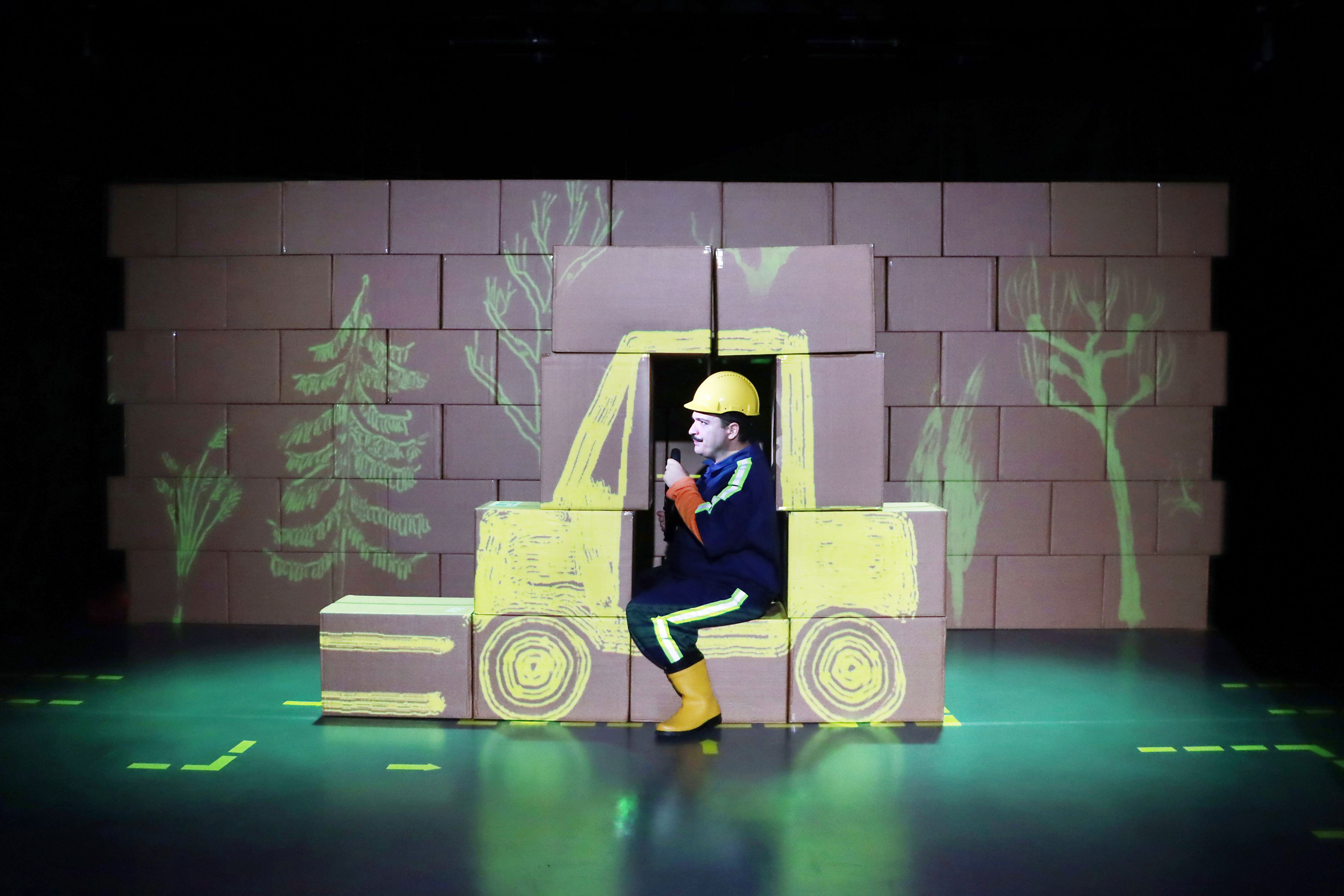 Bild från föreställningen på en man som sitter i en truck byggd av flyttkartonger.