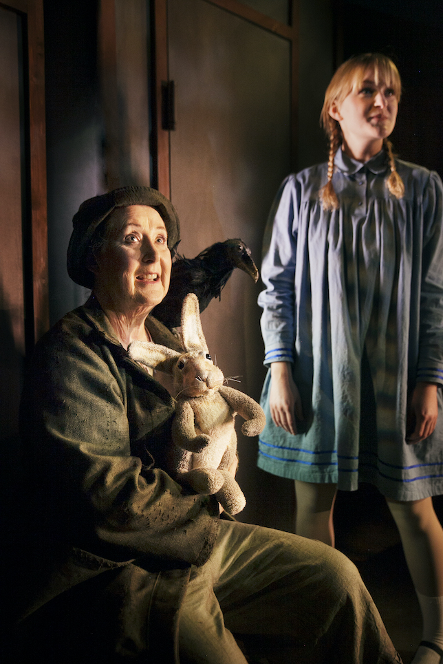 Foto på Mary (Cajsa Svensson) som står upp och Dickon (Gunilla Andersson) som sitter ned med sina djur, kaninen och kråkan.