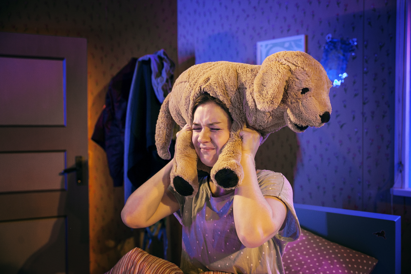 Foto på Zara som sitter i sin säng. Över huvudet och öronen håller hon sitt hund-gosedjur.